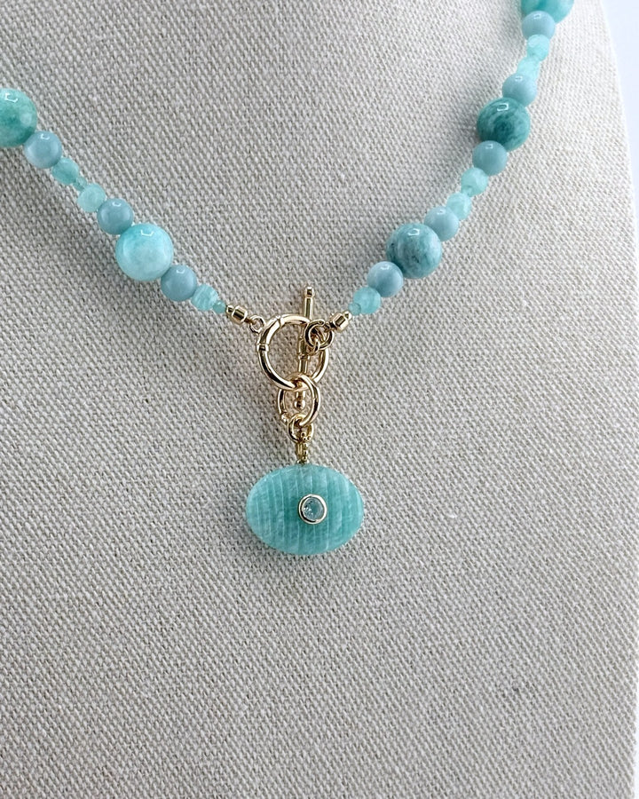 Detail of the carved amazonite oval pendant set with a blue topaz, on a gold toggle