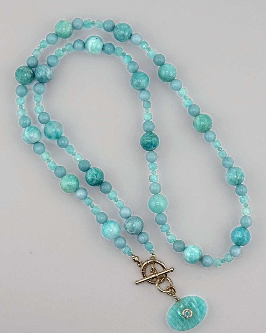Full flat-lay of the amazonite bubble necklace showing the graduated aqua beads and carved oval pendant
