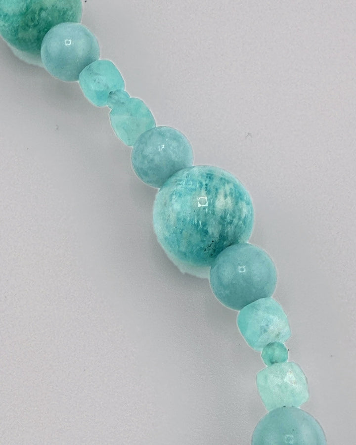 The carved amazonite oval pendant with blue topaz and gold links, close view on a display bust
