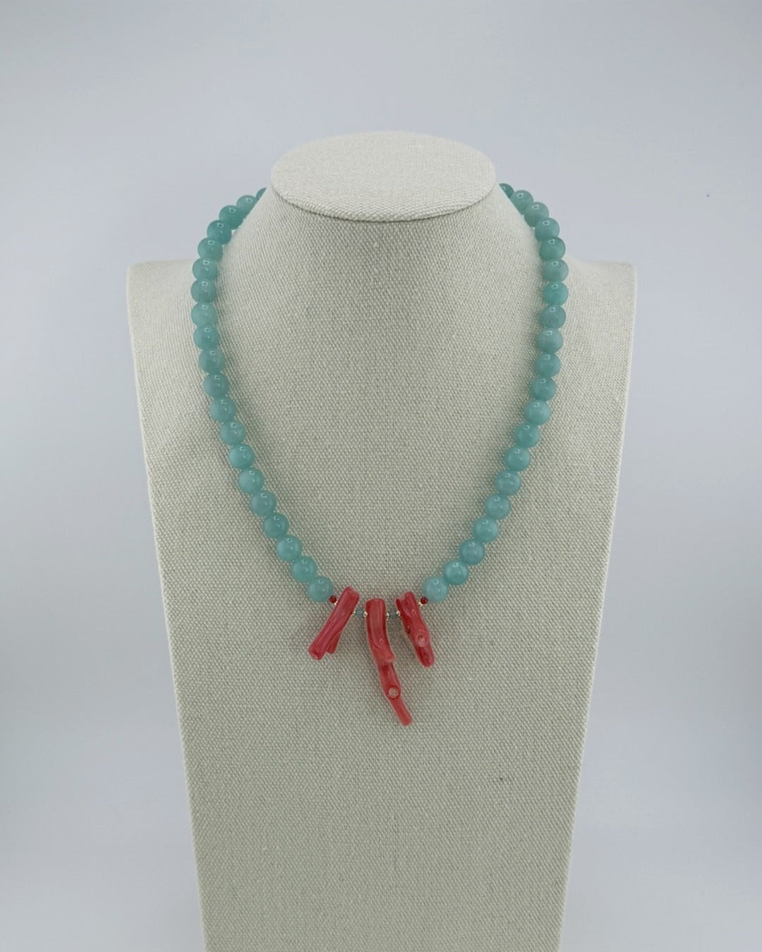 Amazonite and red coral statement necklace, front view on a display bust