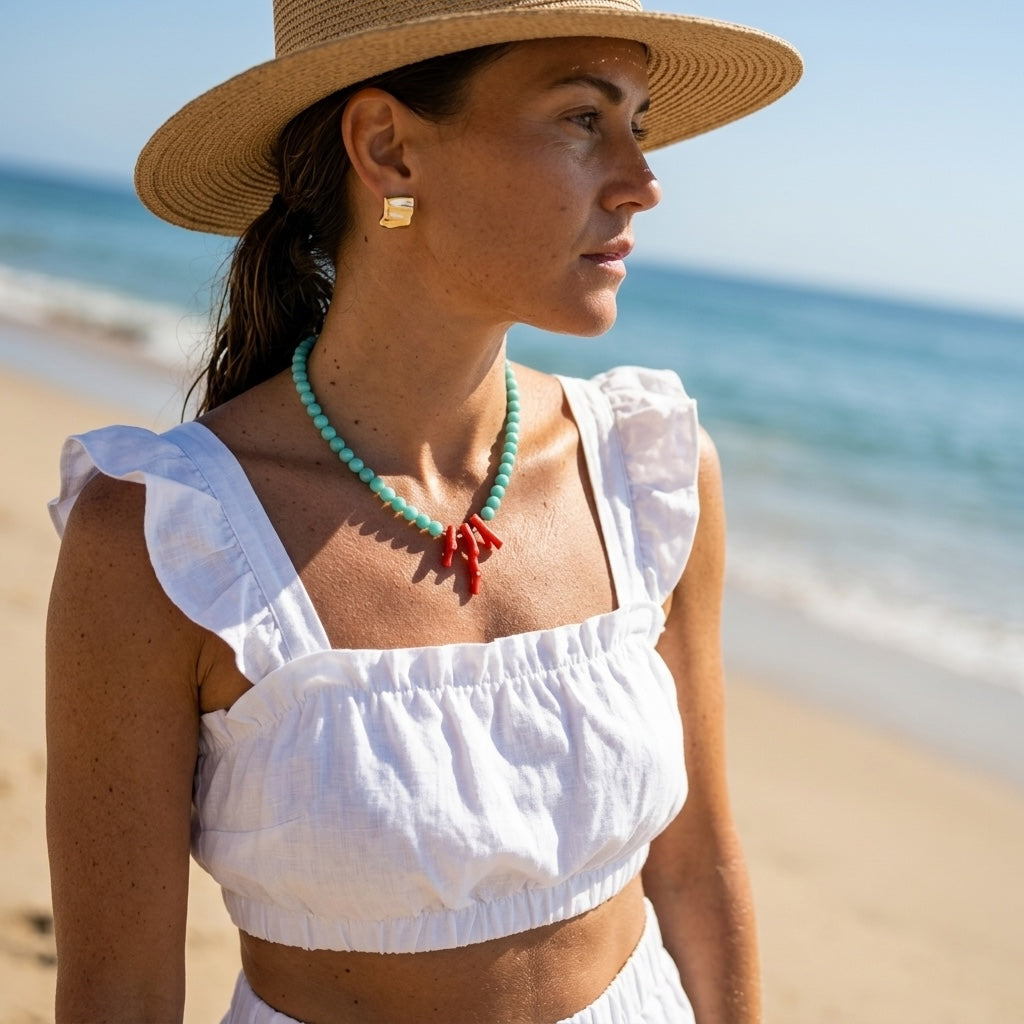 woman in golden sunlight wearing the amazonite and coral necklace with a coral branch pendant