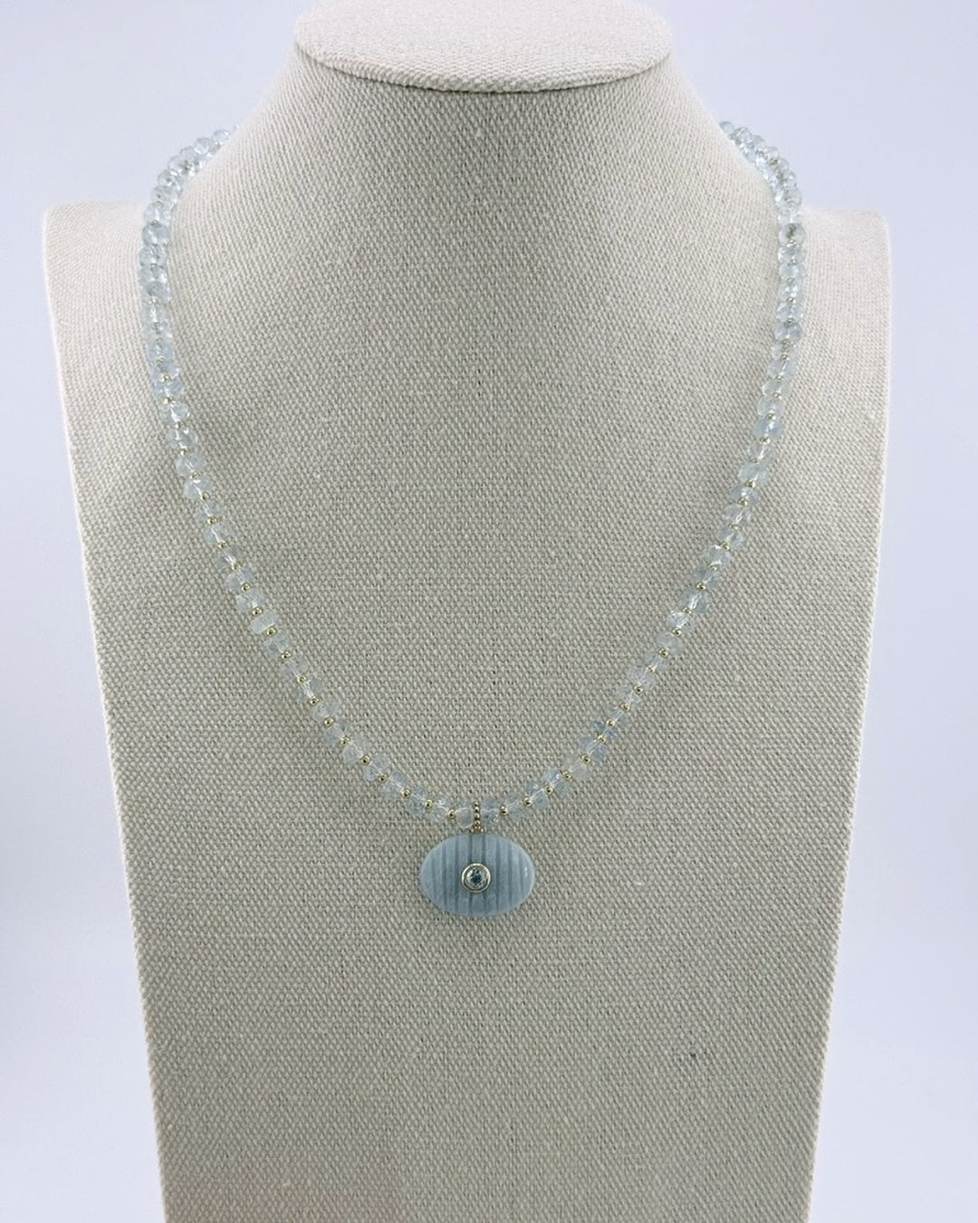 Aquamarine pendant necklace, front view showing the pale faceted beads and gold accents