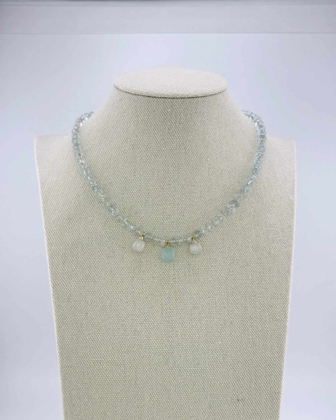 Pale aquamarine necklace with three carved teardrop drops at the front, full view on a display bust