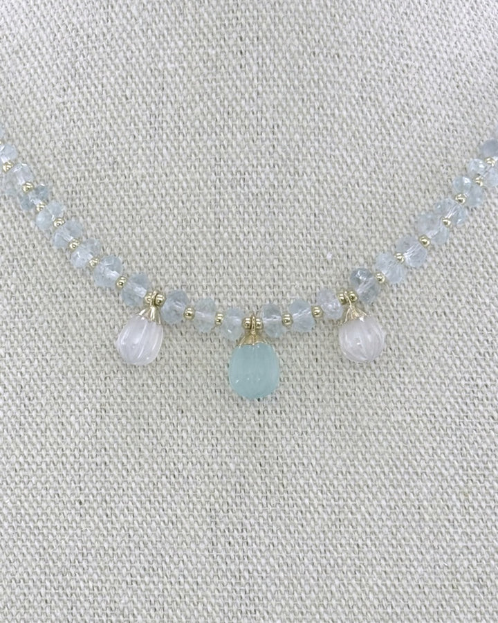 Detail of the three carved drops — a blue chalcedony center flanked by two moonstones — capped in gold on the faceted aquamarine strand
