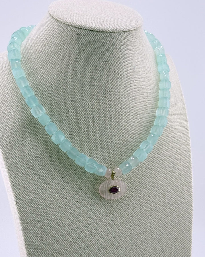 Angled view of the blue chalcedony strand necklace with the rose quartz ruby pendant