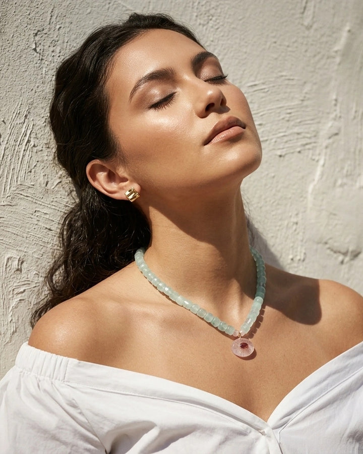 Model in a white off-shoulder linen top wearing the blue chalcedony and rose quartz ruby pendant necklace in warm sunlight