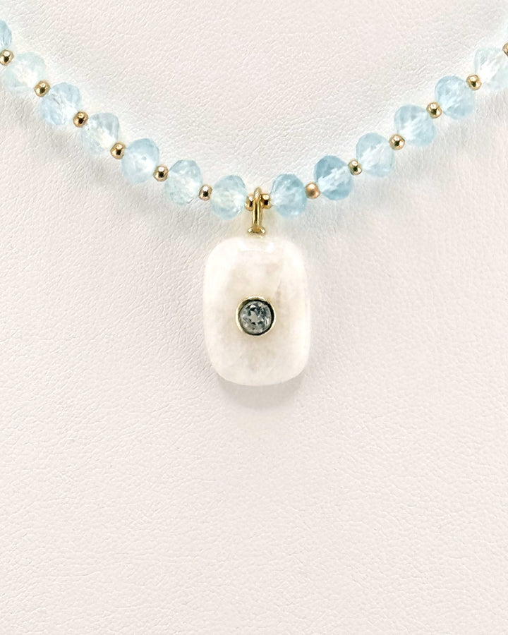 Close view of the carved moonstone pendant set with a single blue topaz