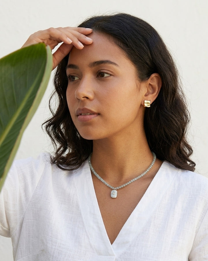 Model in white linen wearing the blue topaz and moonstone pendant necklace