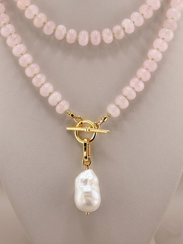 Close-up of faceted peridot accents and a baroque pearl on the rose quartz necklace