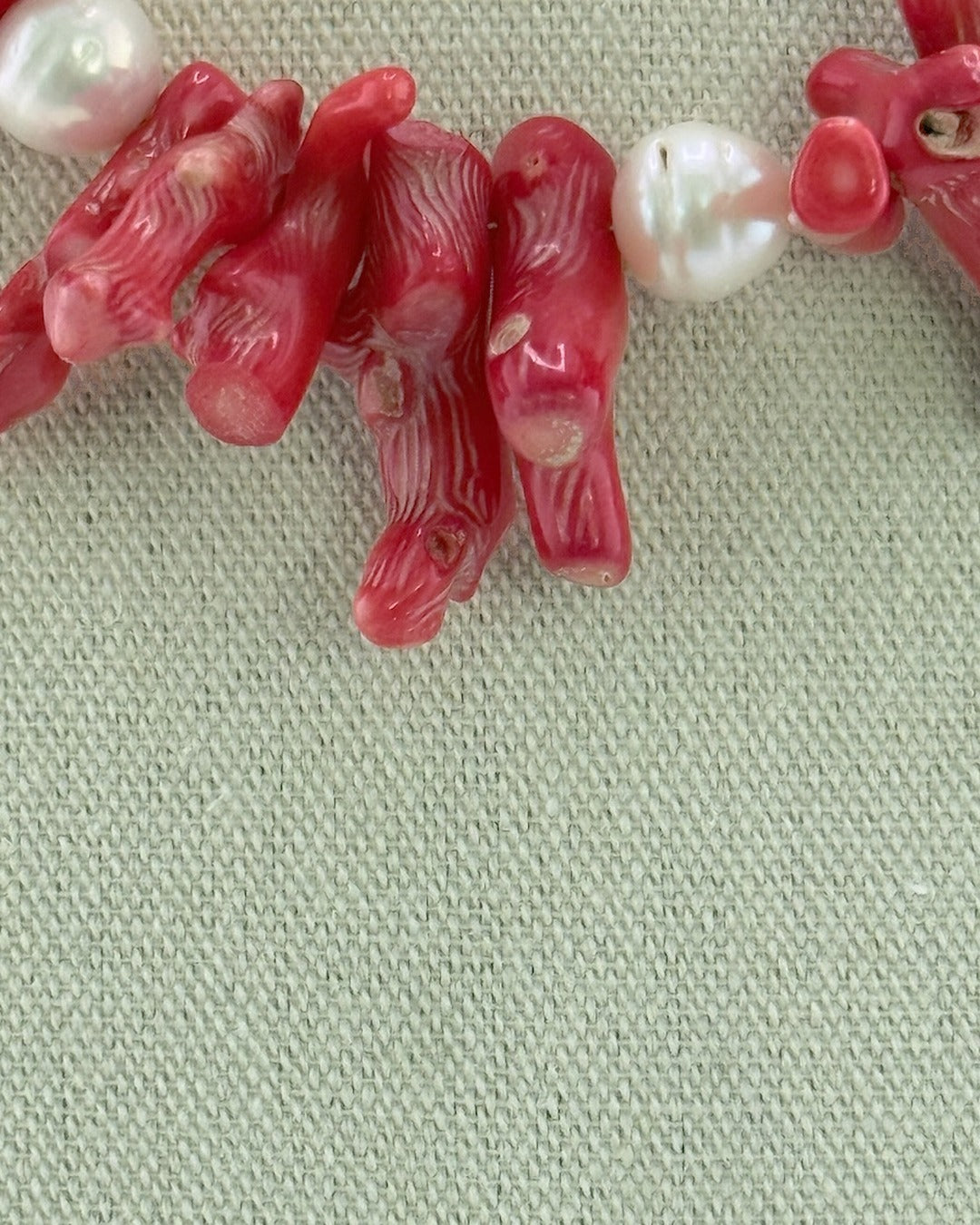 Close-up of the red bamboo coral branches and a white Edison pearl on the statement necklace