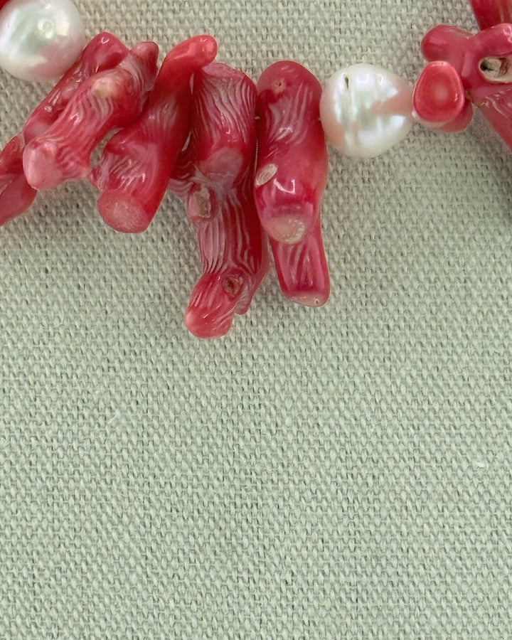 Close-up of the red bamboo coral branches and a white Edison pearl on the statement necklace