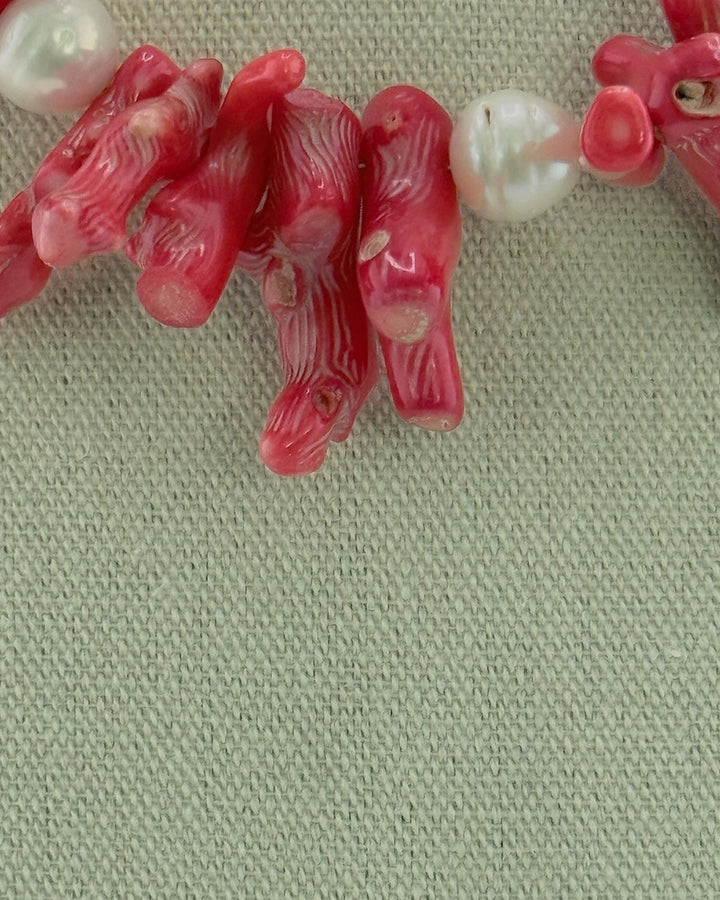 Close-up of the red bamboo coral branches and a white Edison pearl on the statement necklace