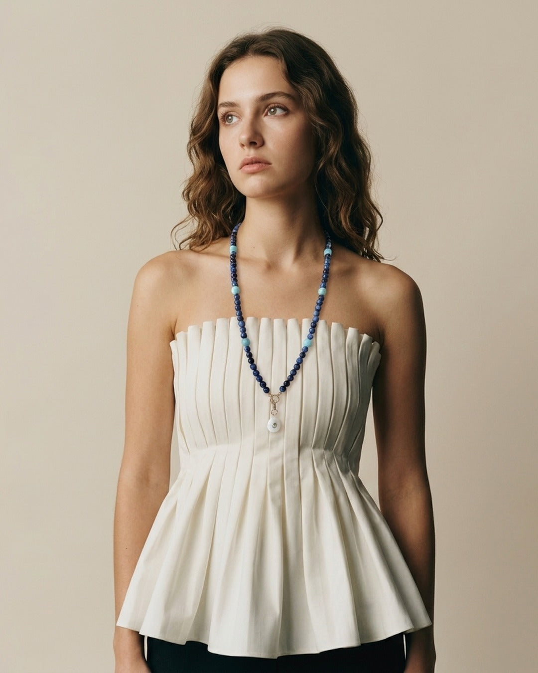 Model in a white pleated top wearing the long kyanite and amazonite necklace with moonstone pendant
