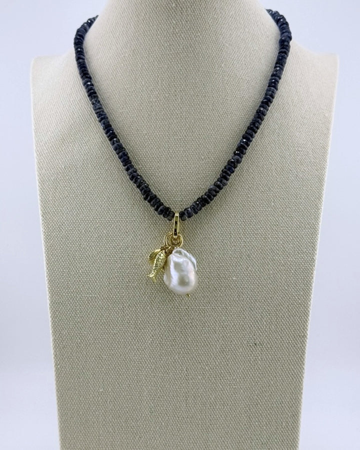 Navy kyanite necklace with a baroque pearl and gold charm drop, front view on a display bust