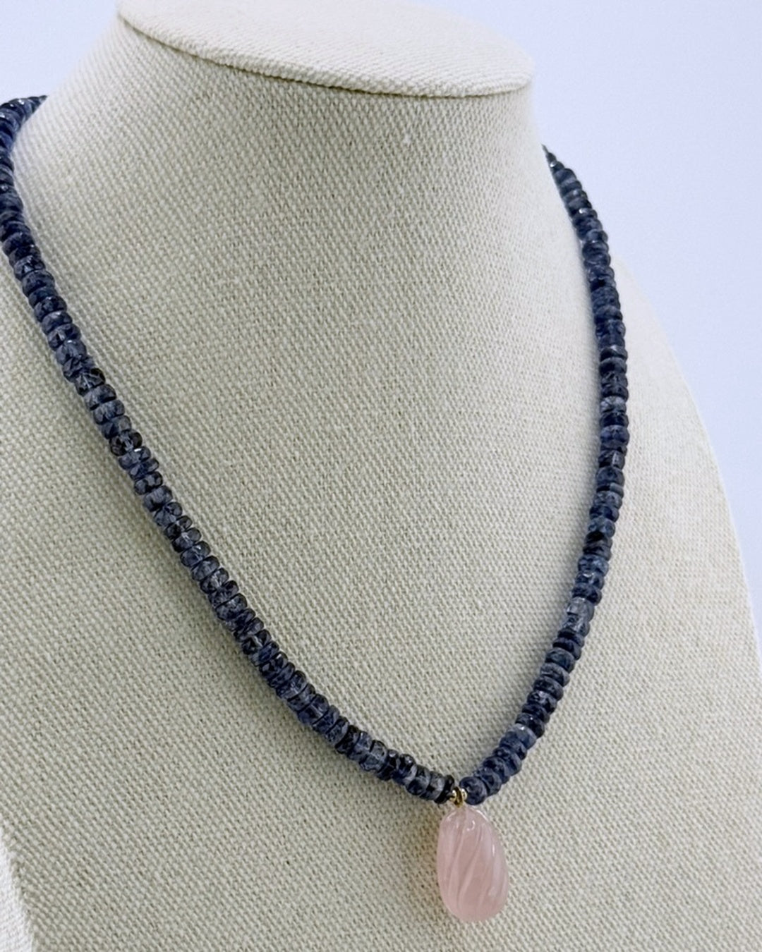 Kyanite and rose quartz necklace, angled full view showing the translucent navy strand and pink drop