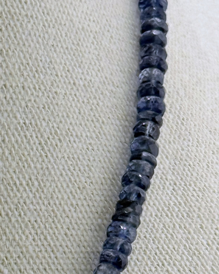 Detail of the carved rose quartz teardrop on a gold bail against the faceted kyanite strand