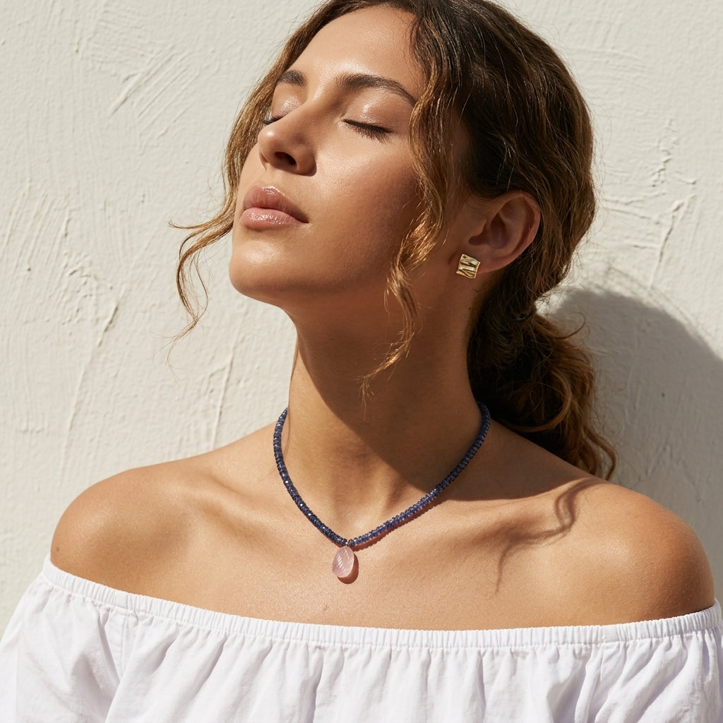 woman in a white off-shoulder top wearing the kyanite and rose quartz necklace in golden sunlight