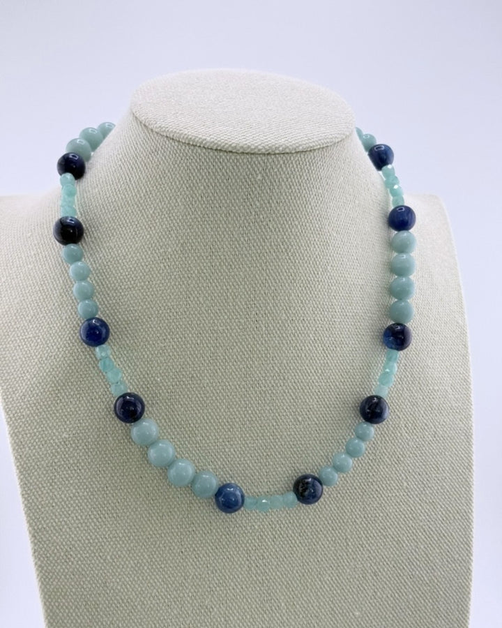 Aqua amazonite bead necklace with deep-blue kyanite accents and gold clasp on a linen bust