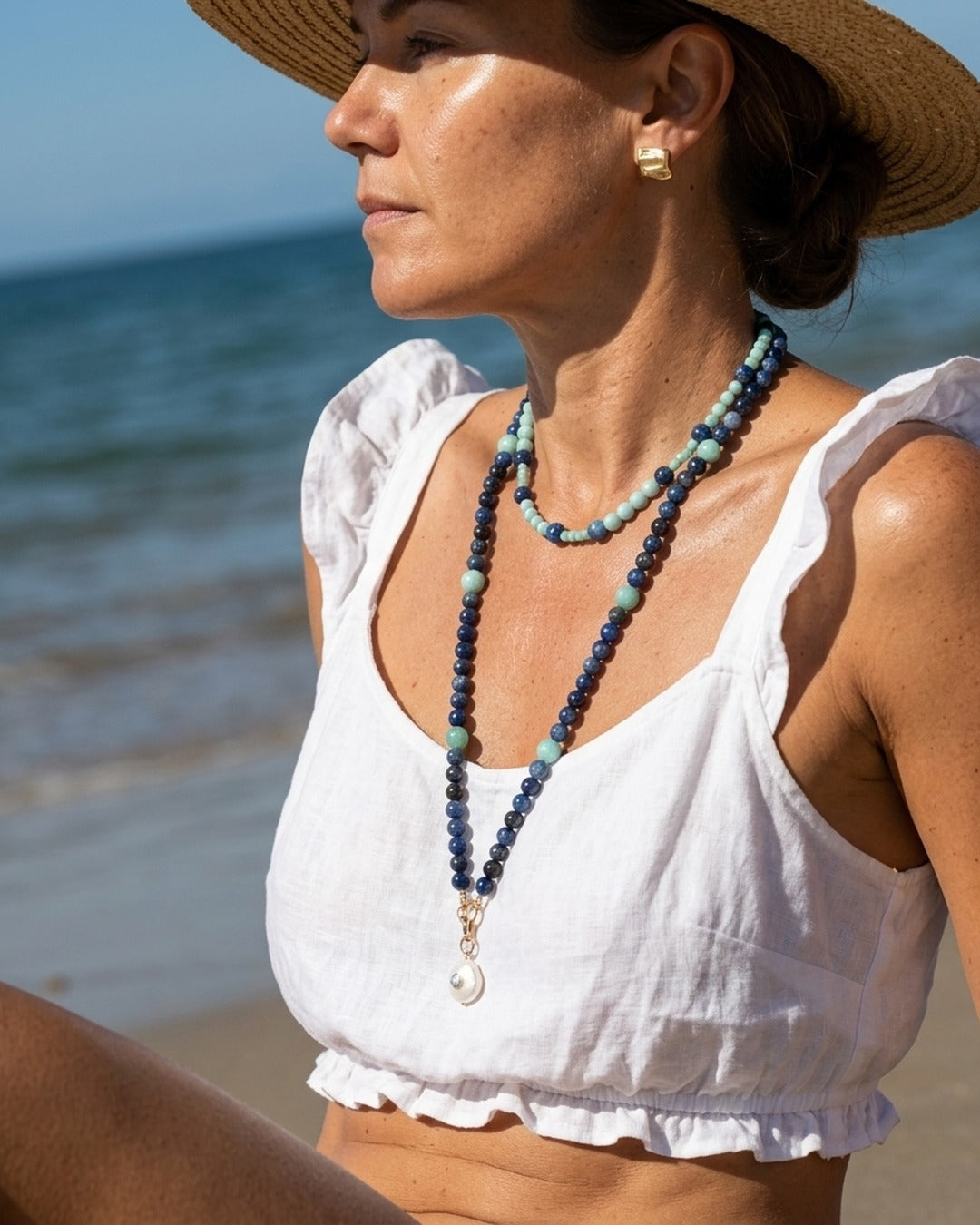 Model on the beach wearing the short kyanite and amazonite necklace layered over the longer pendant version