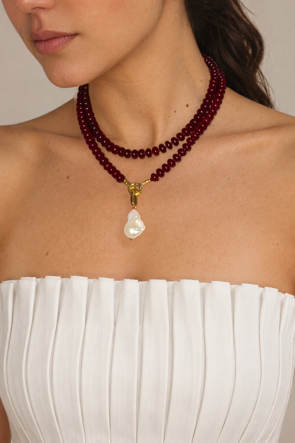 Lulu Necklace in Burgundy worn doubled with the pearl charm, model with head turned
