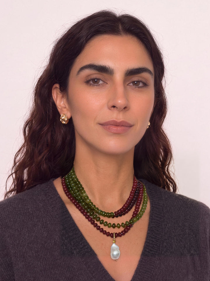 Three Lulu necklaces layered on a model, with a cultured baroque pearl charm