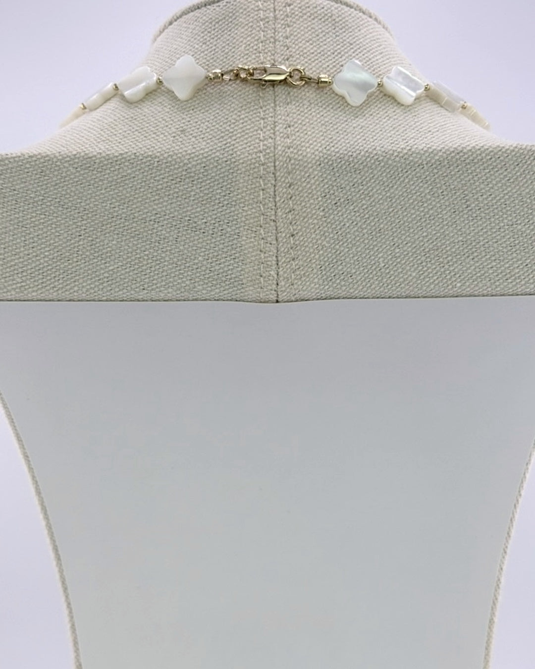 Mother of pearl and kyanite necklace, front view showing the white quatrefoil beads and gold accents