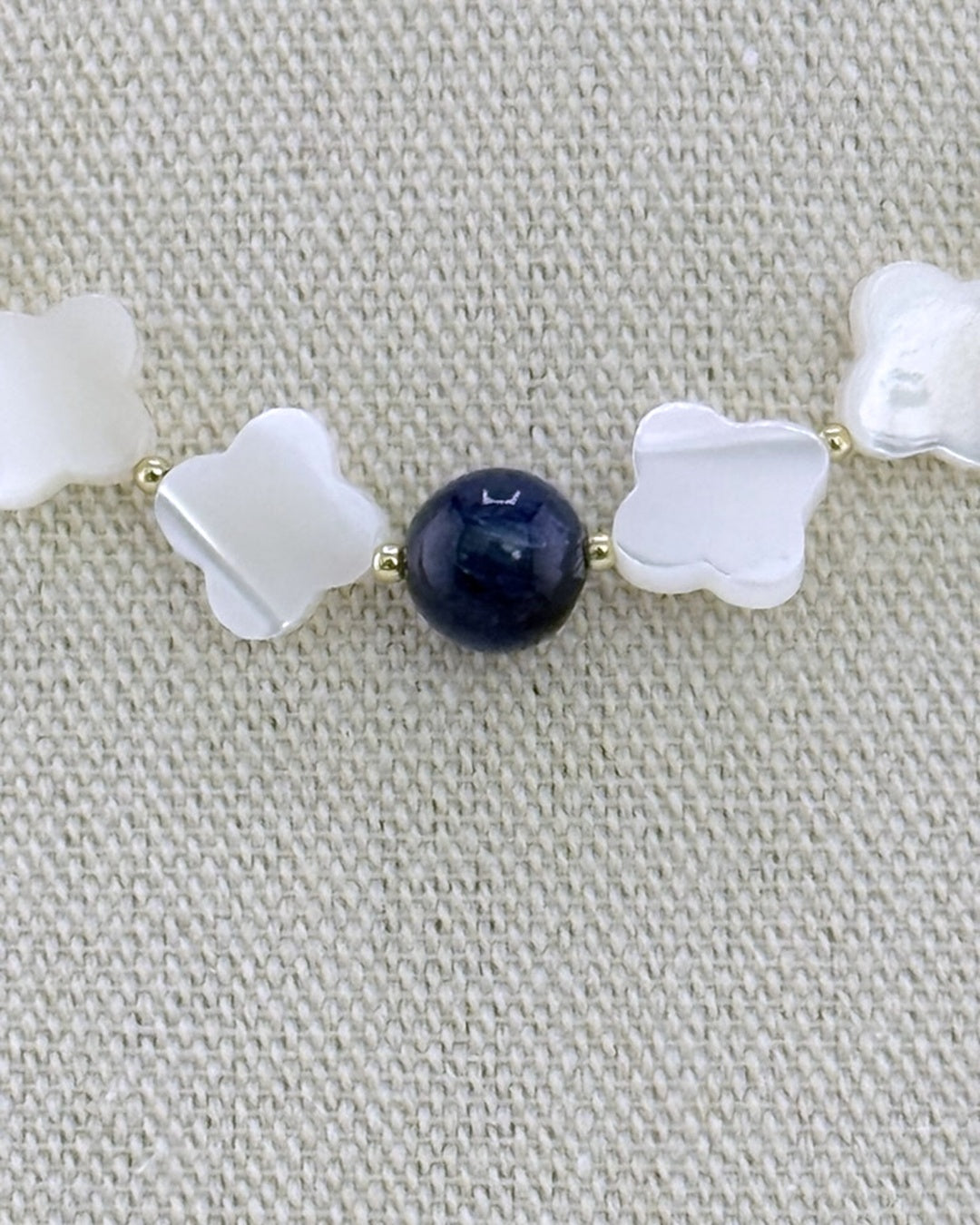 Detail of the mother of pearl quatrefoils and the central navy kyanite bead with small gold accent beads