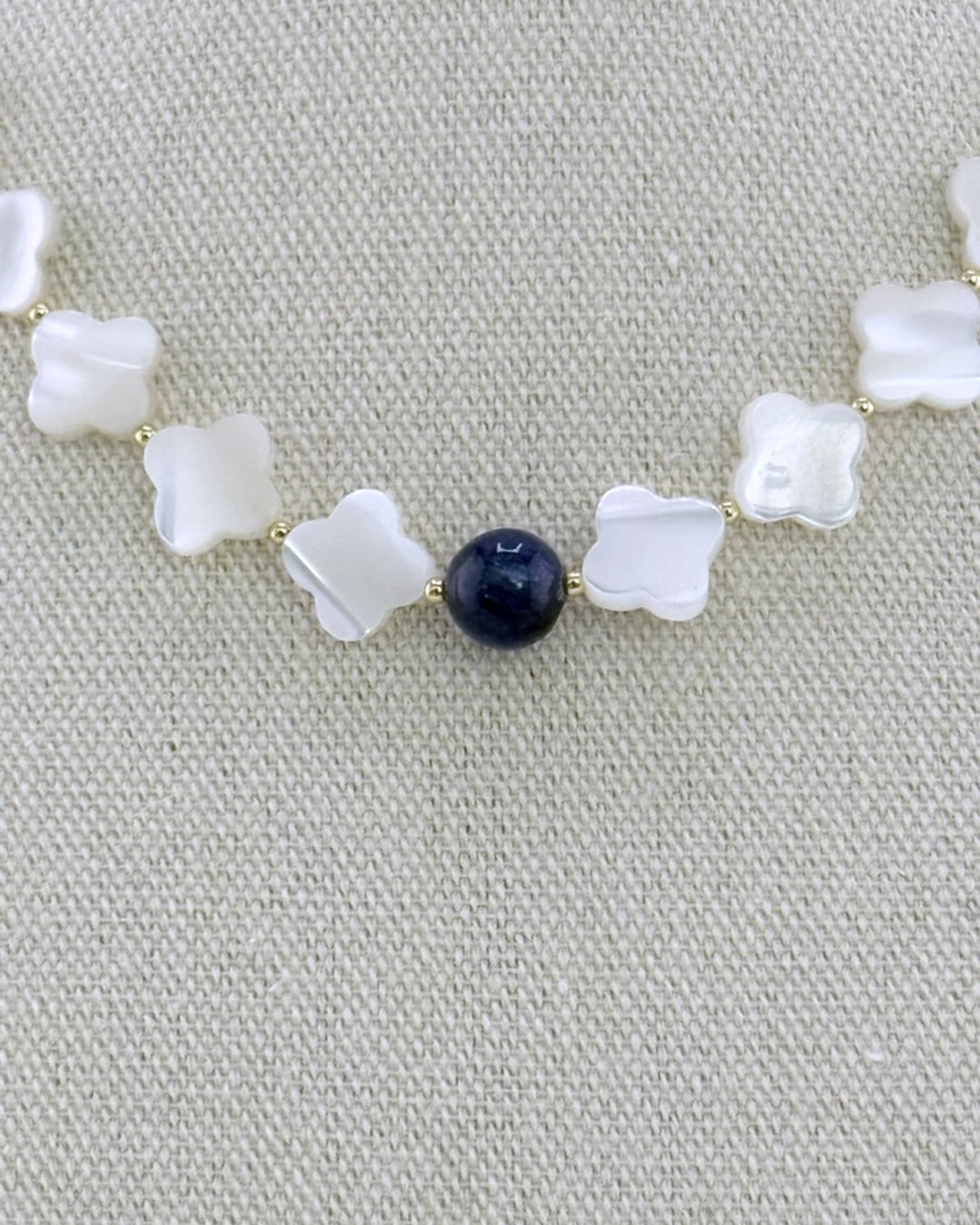 Close-up macro of the pearlescent mother of pearl clover beads and the deep-blue kyanite center bead