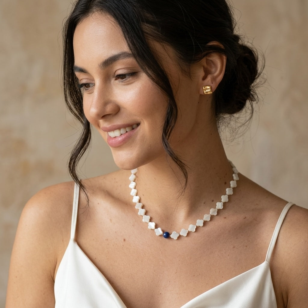 woman in a white cami wearing the mother of pearl and kyanite necklace, the navy bead resting at the collarbone