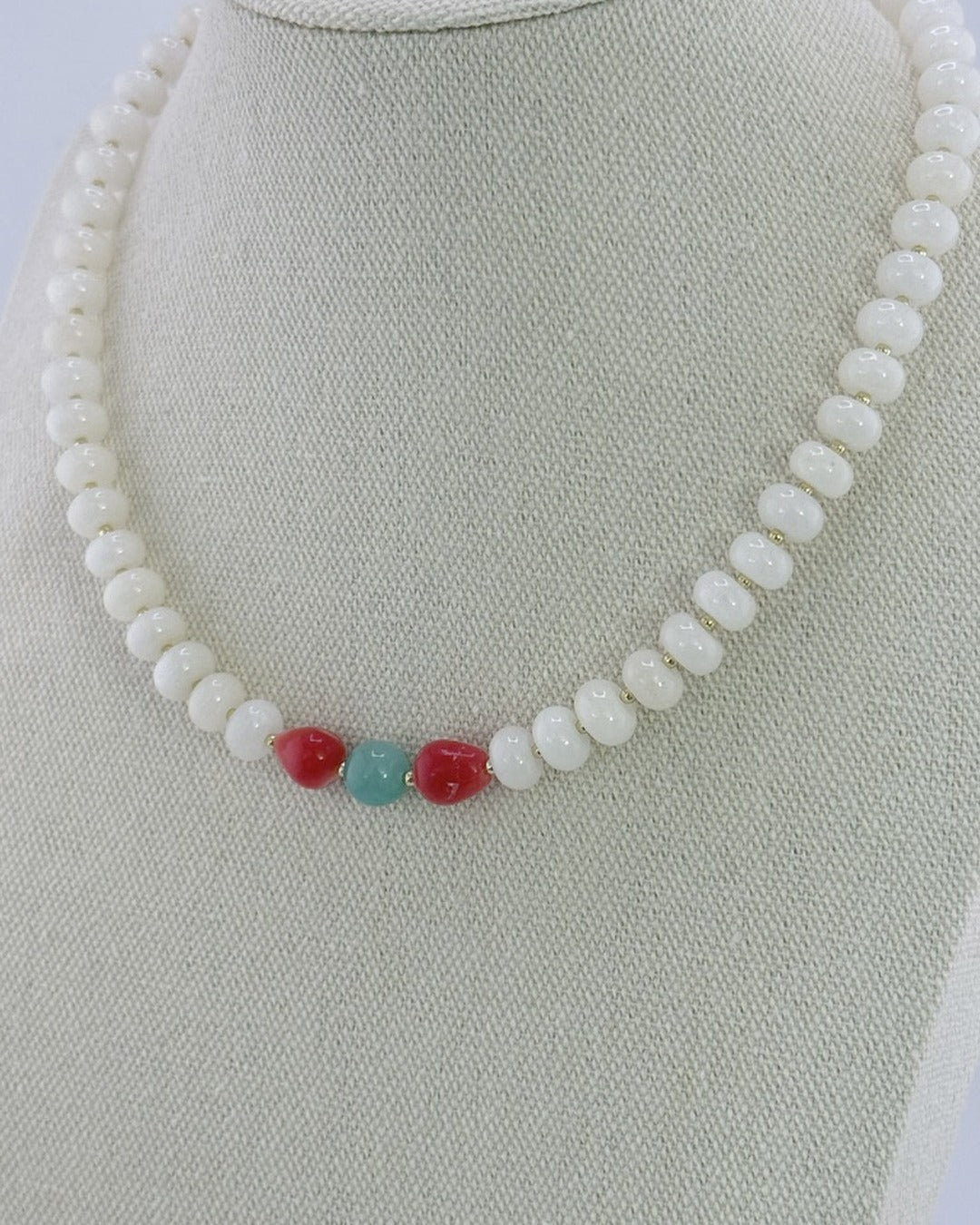 White jade beaded necklace with a pomegranate coral and amazonite center, front view on a display bust