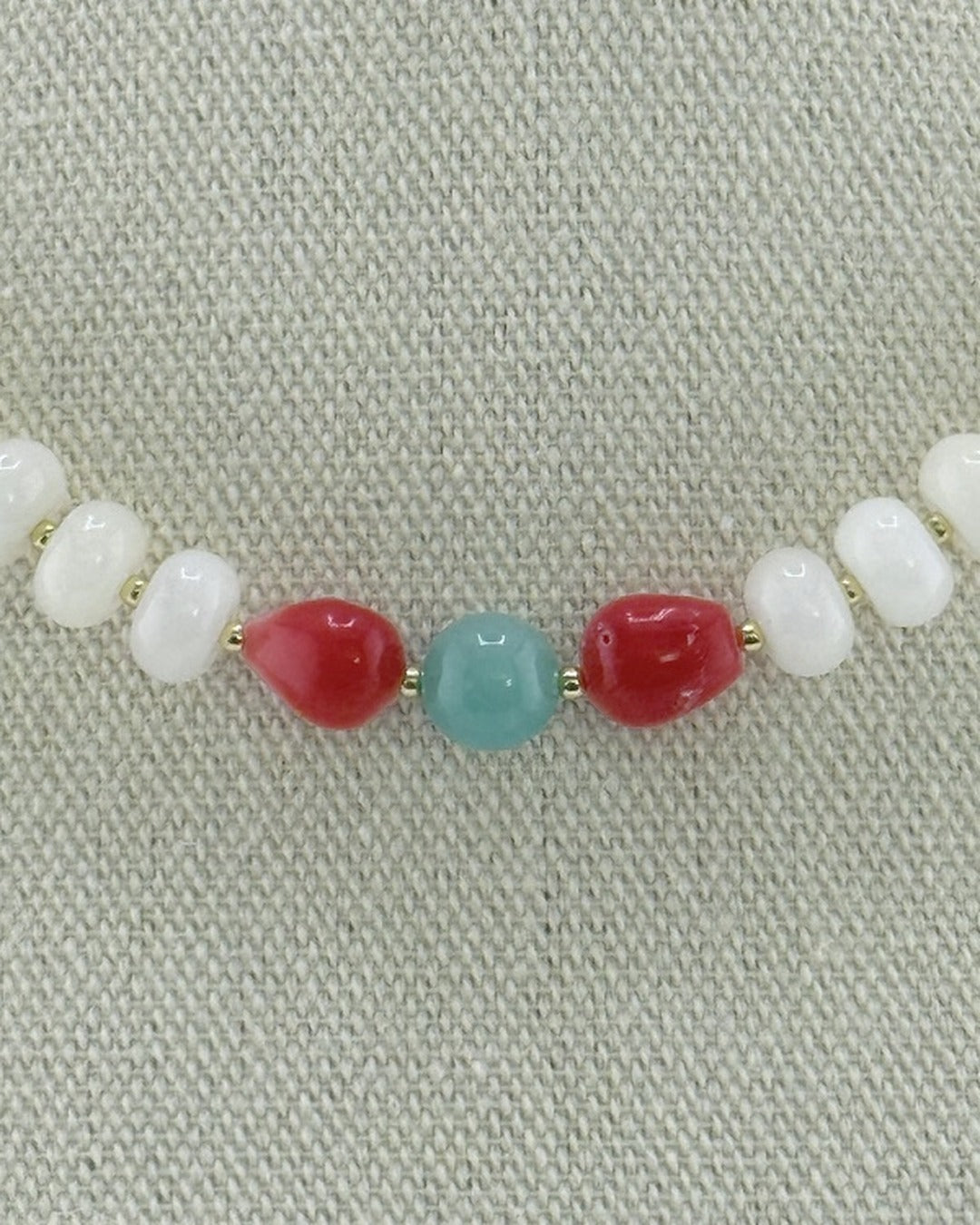 Close-up of the pomegranate bamboo coral and amazonite center on the white jade necklace